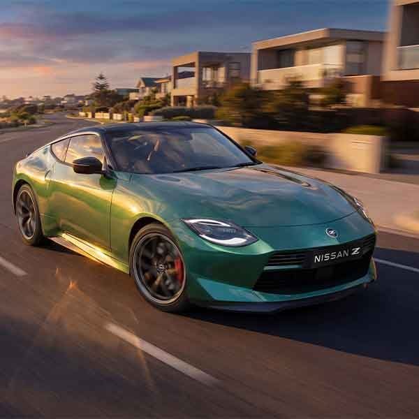 Nissan Z Coupe driving along a coast road with houses in the background