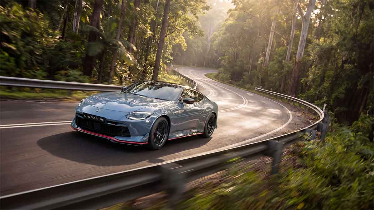 Nissan Z driving along a winding road surrounded by trees and bush.
