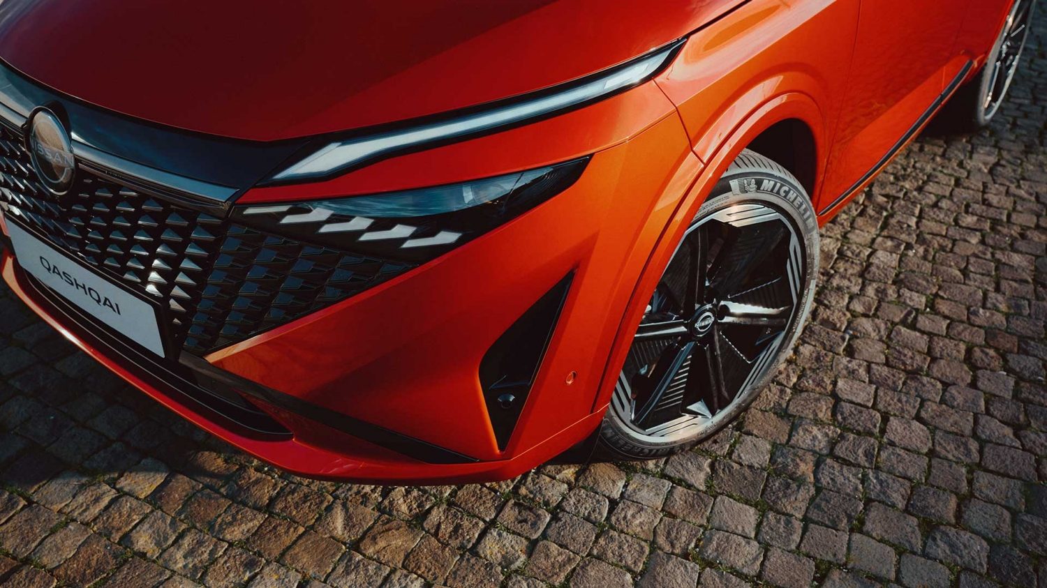 Nissan Qashqai e-Power 3/4 front static shot in front of building with woman walking towards car - Hybrid SUV
